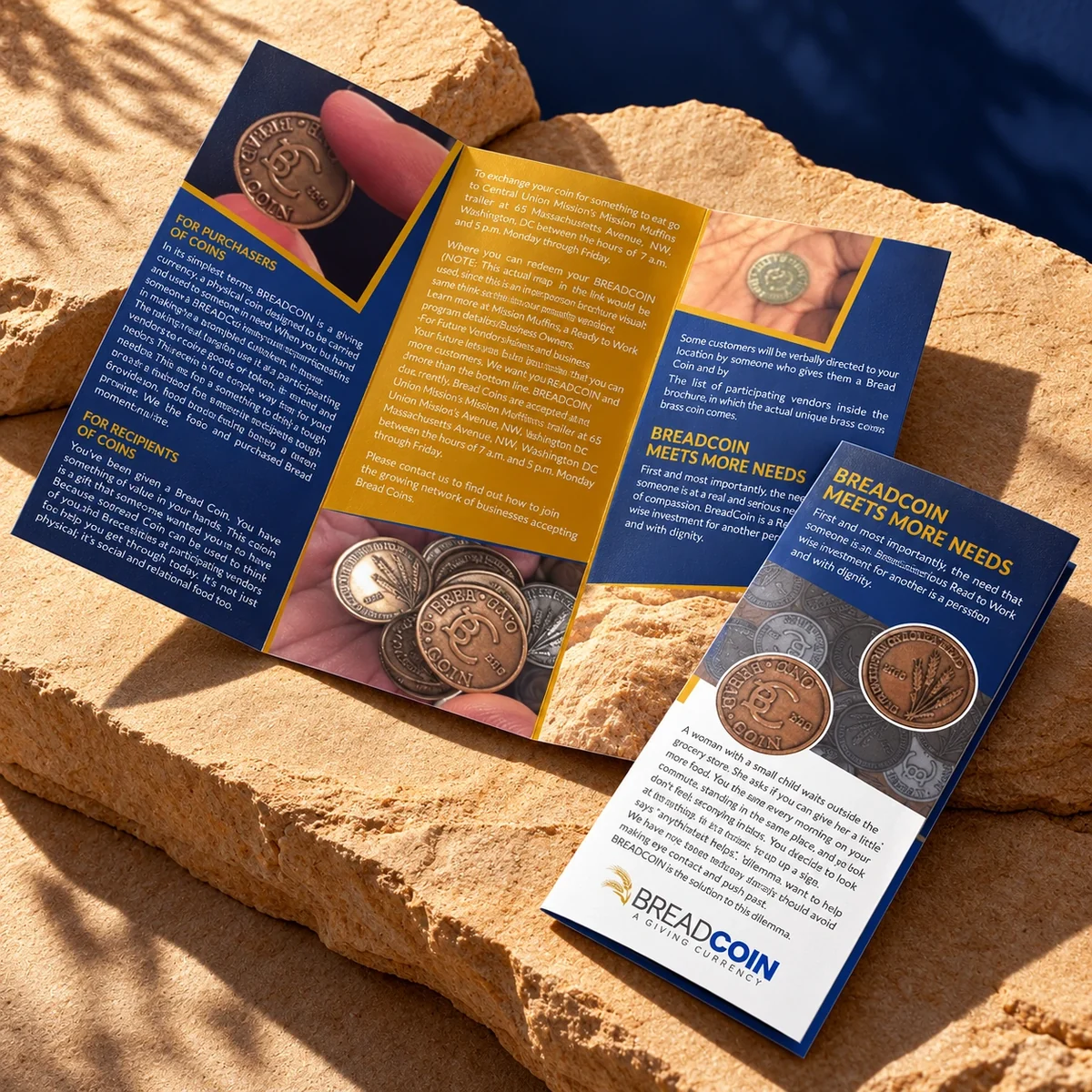 Open and folded Breadcoin brochures in navy and yellow on a warm stone surface